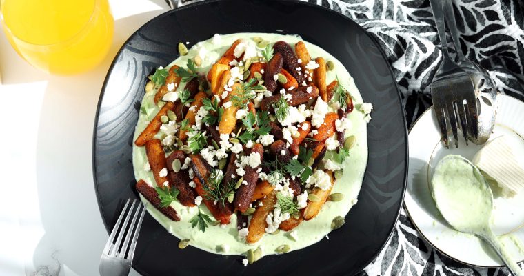 Colorful Roasted Baby Carrots served on a black plate with Herbed Whipped Feta Sauce